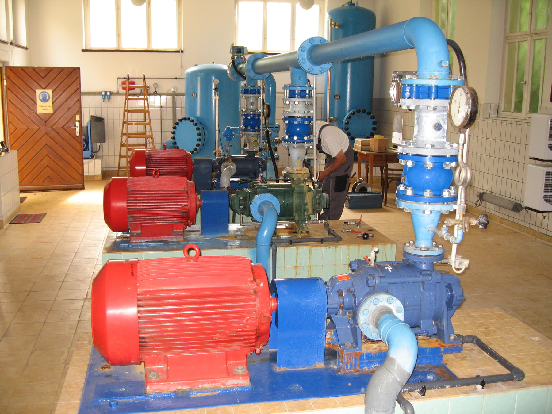 Industrielle Pumpenanlage in einem Technikraum mit roten Motoren und blauen Leitungen &ndash; Anwendung in Wasseraufbereitung und Versorgungstechnik
